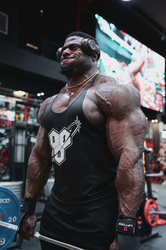 A very muscular man is lifting a barbell in a gym.