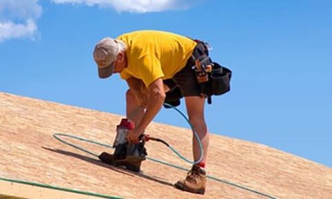 Roofer installs bitumen roof shingles — Roofing Services in Dr. Santa Maria, CA