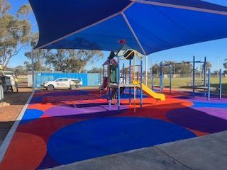 Playground with blue canopy, colorful flooring, and play structures — Dubbo Premier Landscapes in Dubbo, NSW