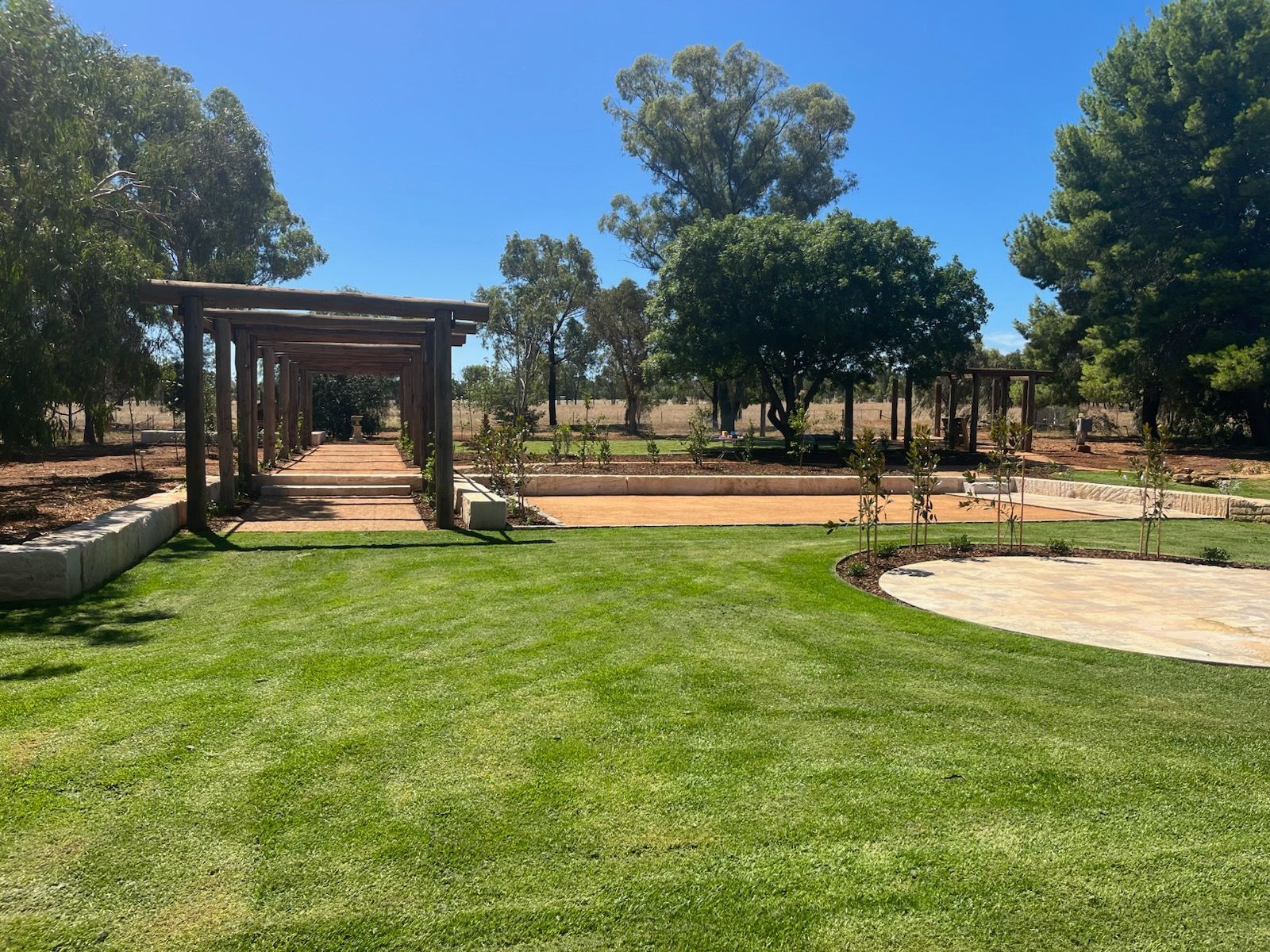 Lush green lawn leads to a pergola-covered pathway — Dubbo Premier Landscapes in Dubbo, NSW