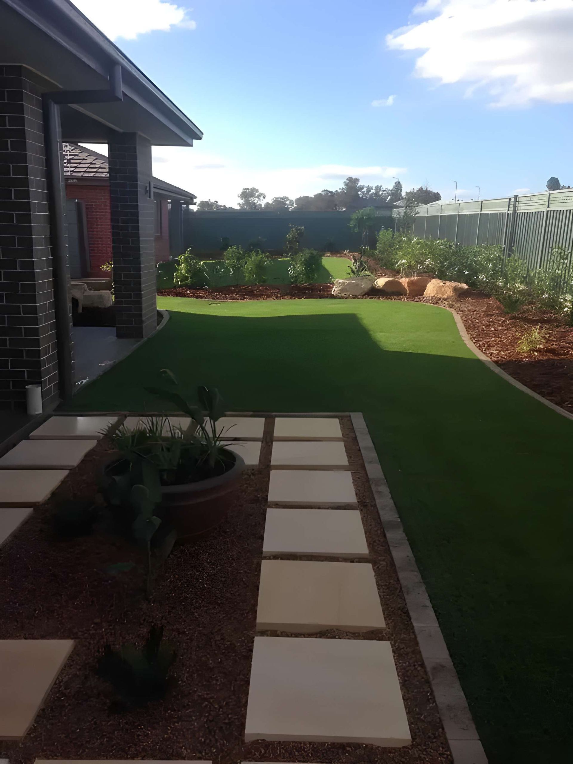 Backyard Landscape With Artificial Turf, Stone Path, and Garden Beds — Dubbo Premier Landscapes in Dubbo, NSW