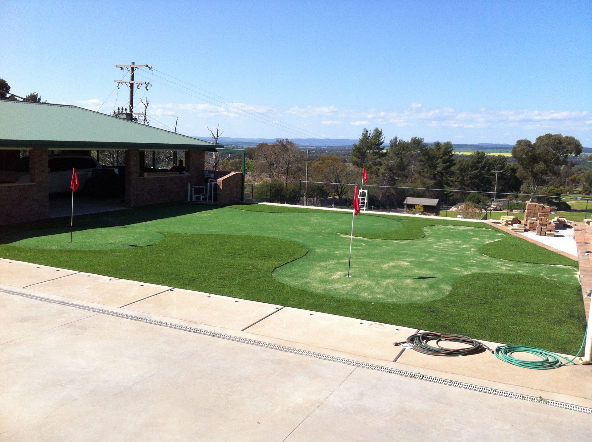 Green putting greens with flags, near a building — Dubbo Premier Landscapes in Dubbo, NSW