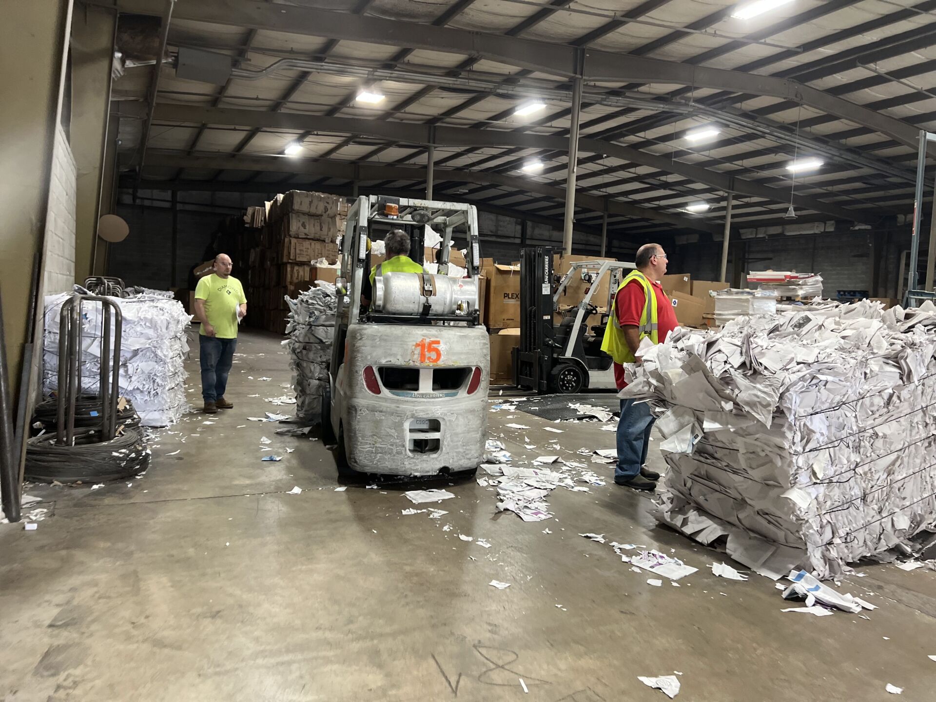 A man is standing next to a forklift in a warehouse.