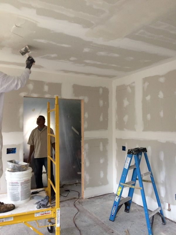 A man is painting the ceiling of a room