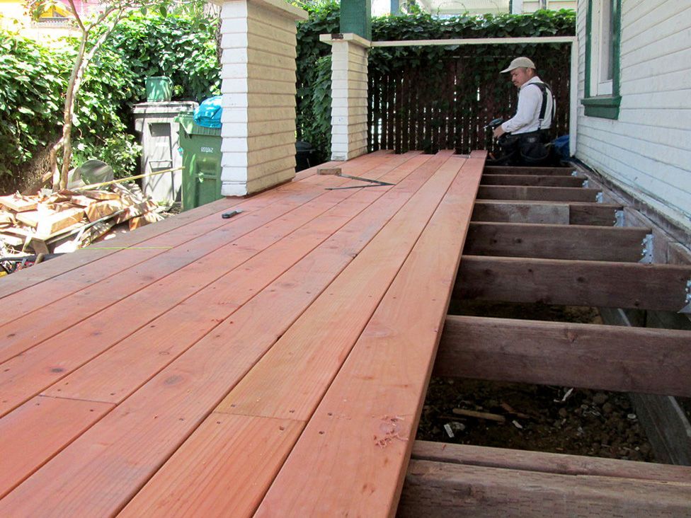 A man is sitting on a wooden deck under construction