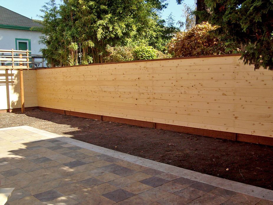 A wooden fence is surrounded by dirt and trees
