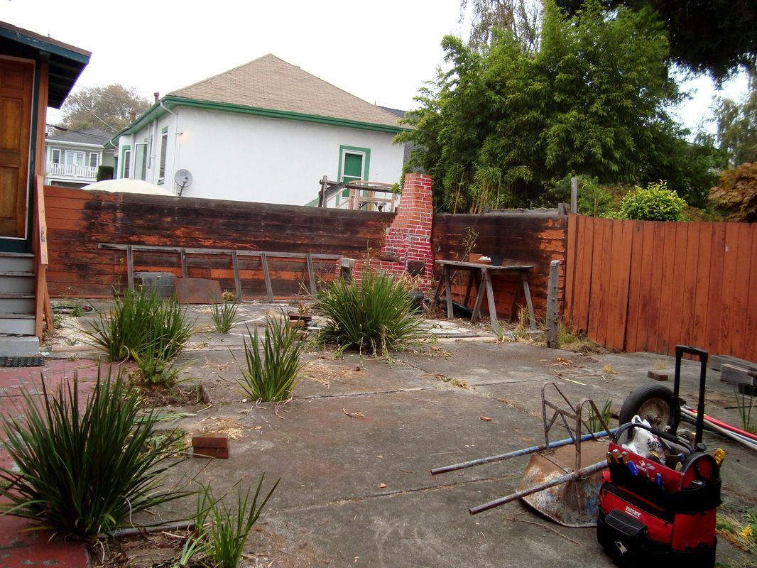 A backyard with a brick wall and a red fence