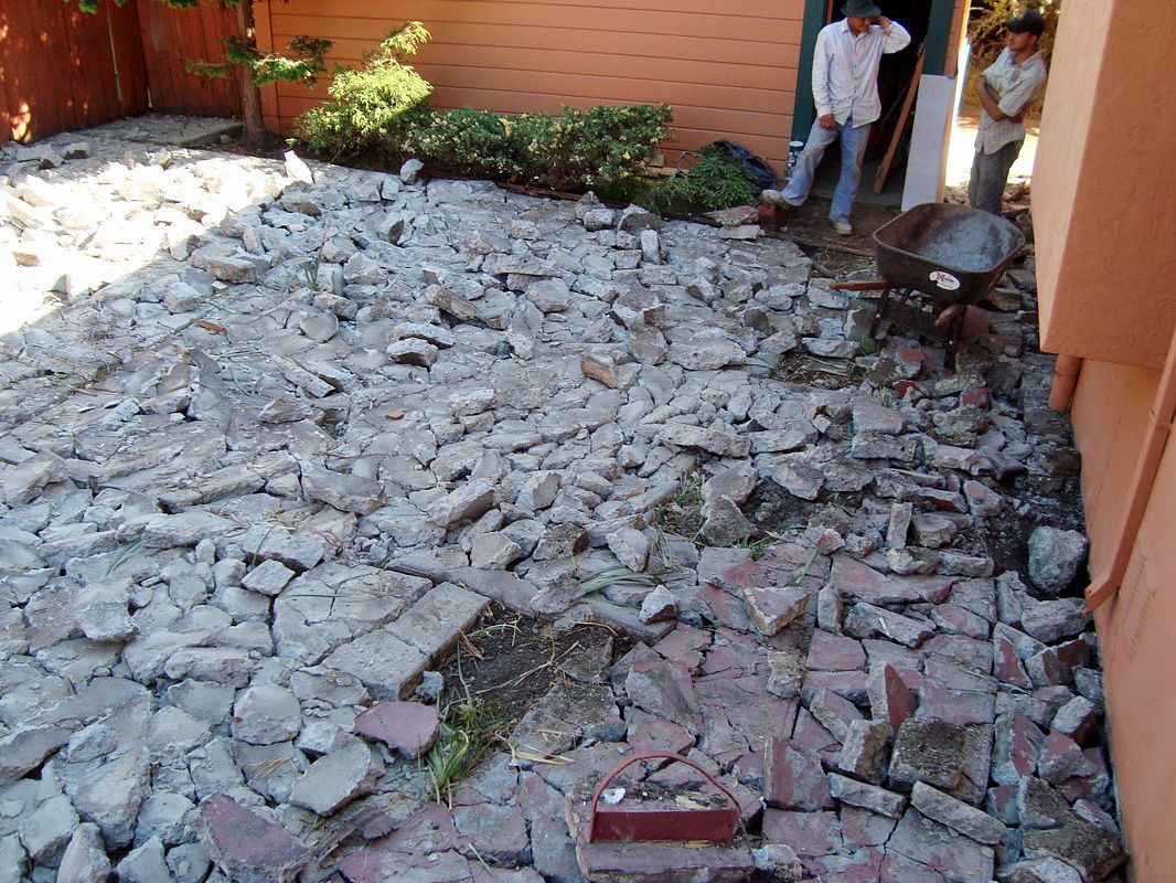 A man is standing in a doorway next to a pile of bricks.