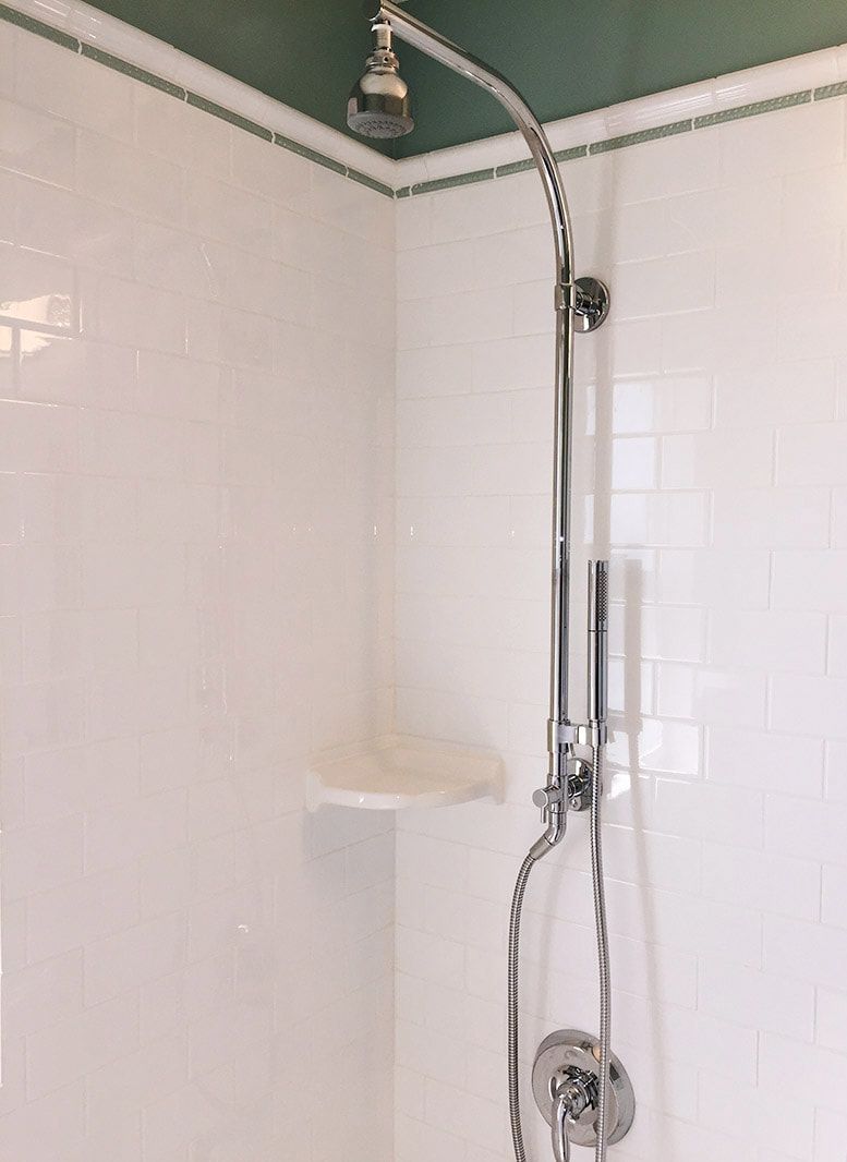 A shower head is hanging from the ceiling in a bathroom.