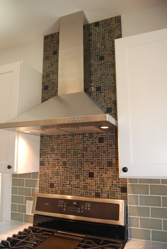 A kitchen with a stove and a hood above it