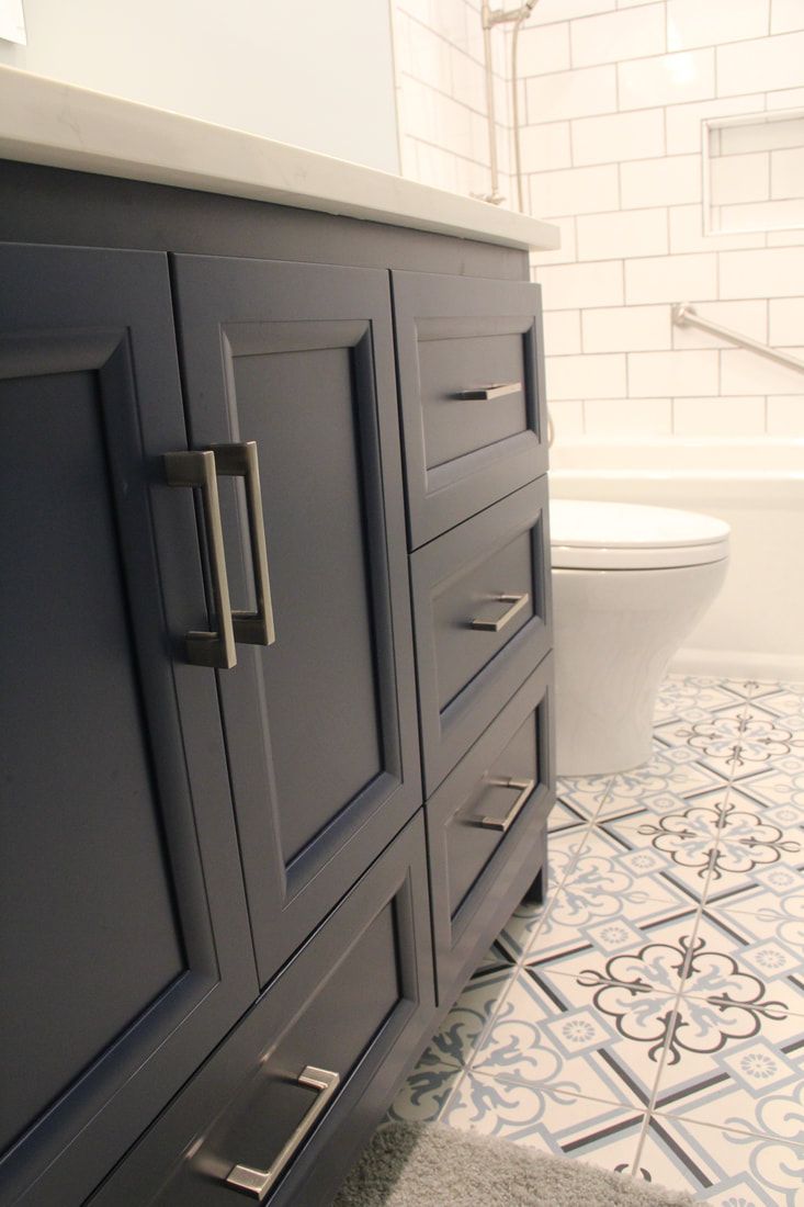 A bathroom with blue cabinets , a toilet , and a bathtub.