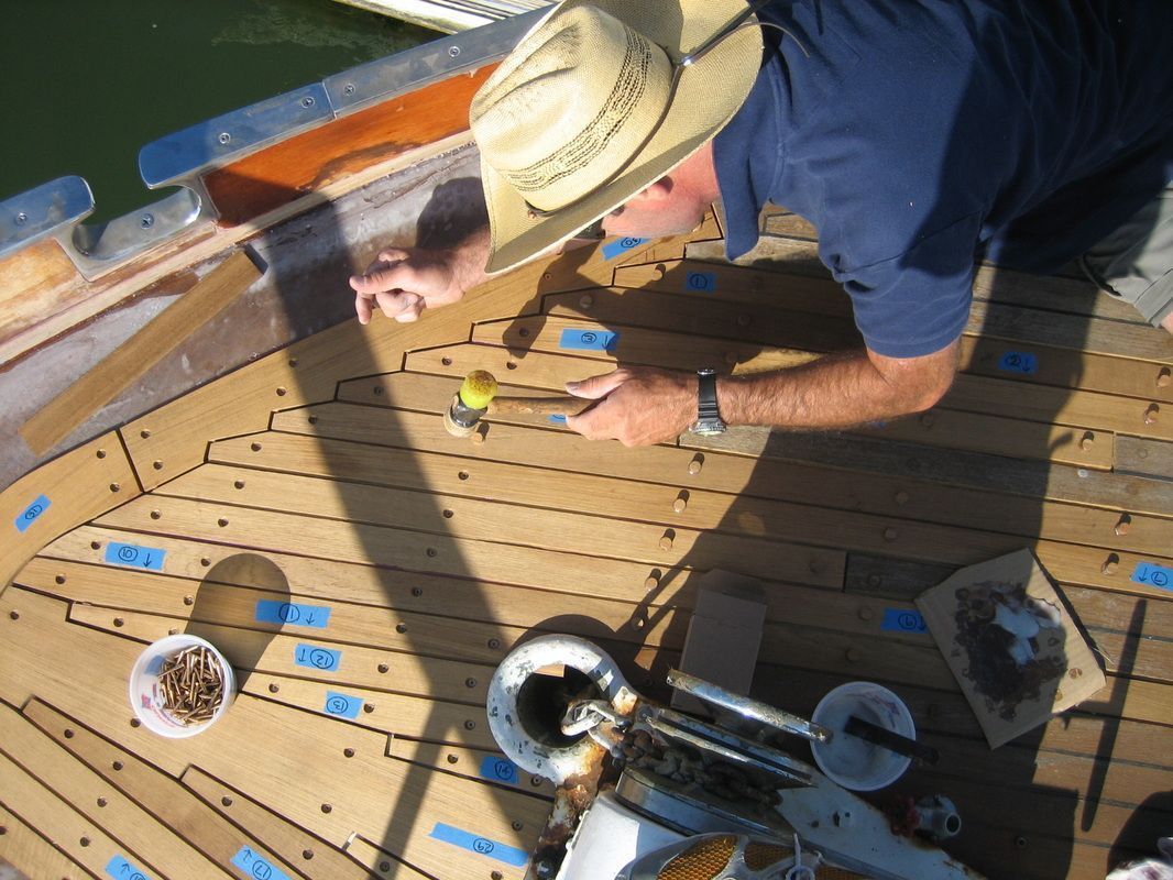 A man wearing a cowboy hat is working on a boat