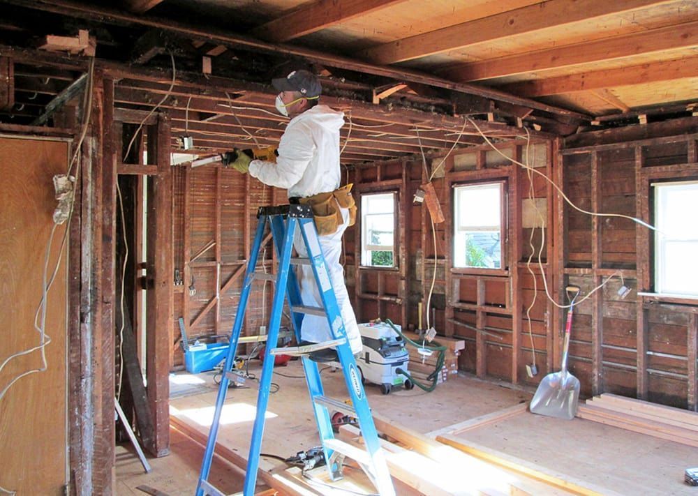 A man is standing on a ladder in a room.