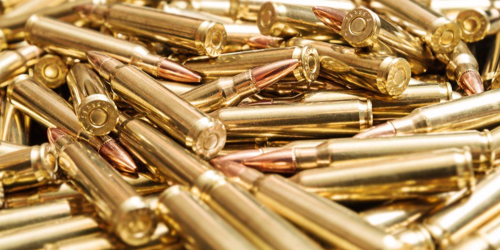A pile of gold bullets on a white surface.