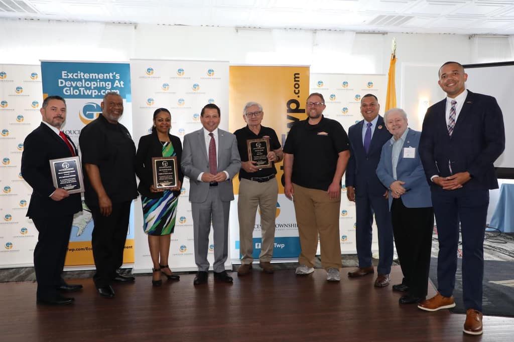 A group of people standing next to each other in a room holding awards.