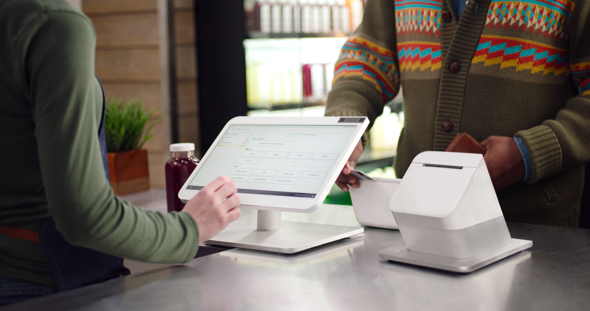 A woman is using a tablet to pay for food at a restaurant.
