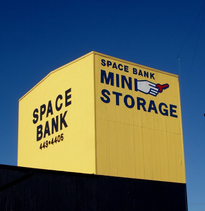 Yellow Space Bank Mini Storage building against a blue sky.