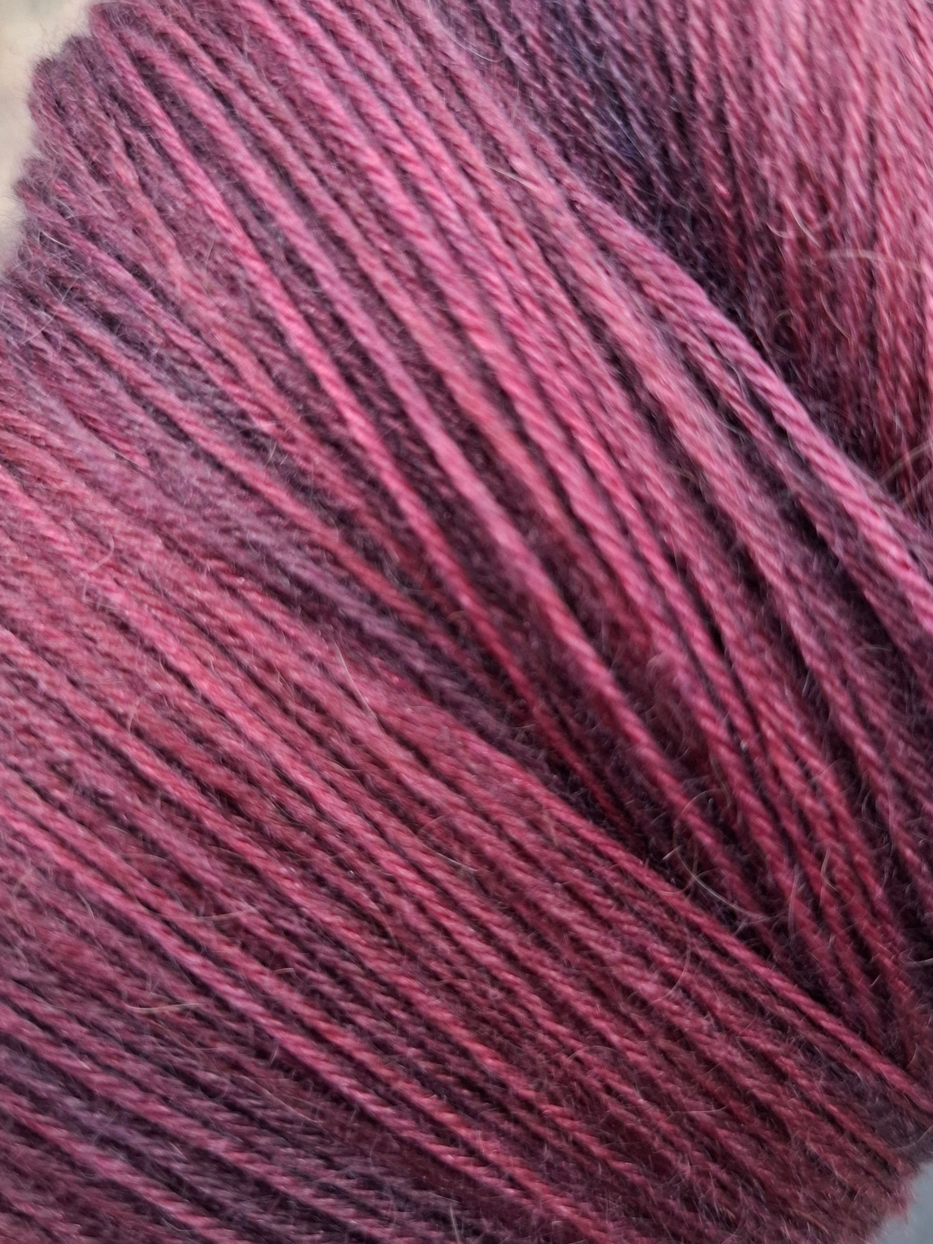 Close-up van een streng handgeverfd garen in tinten blauw, blauwgroen, groen en paars.