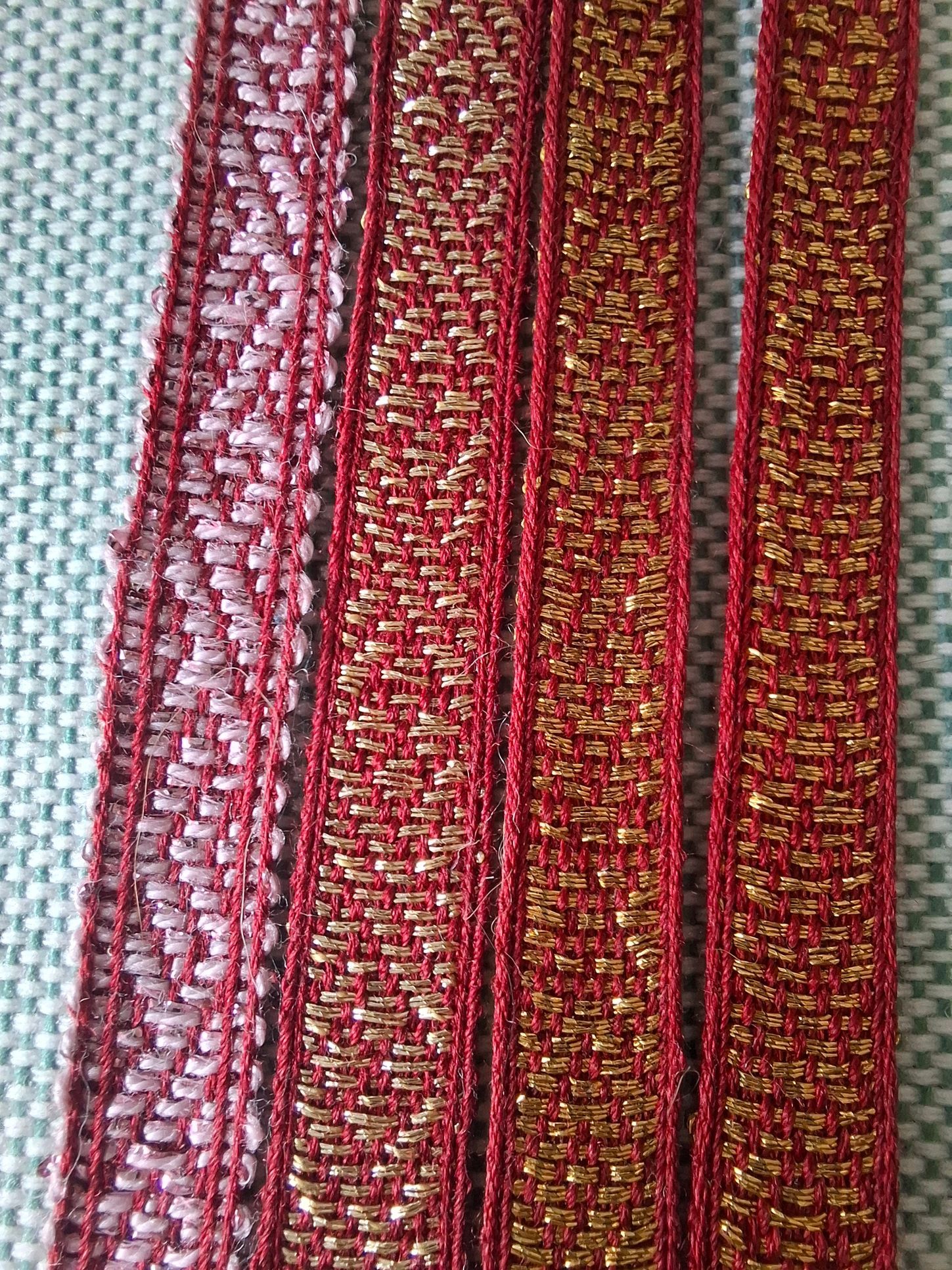 Vier rode en gouden decoratieve stoffen randen, waarvan één met witte accenten, verticaal gerangschikt. Brokaat zijde bandweven.