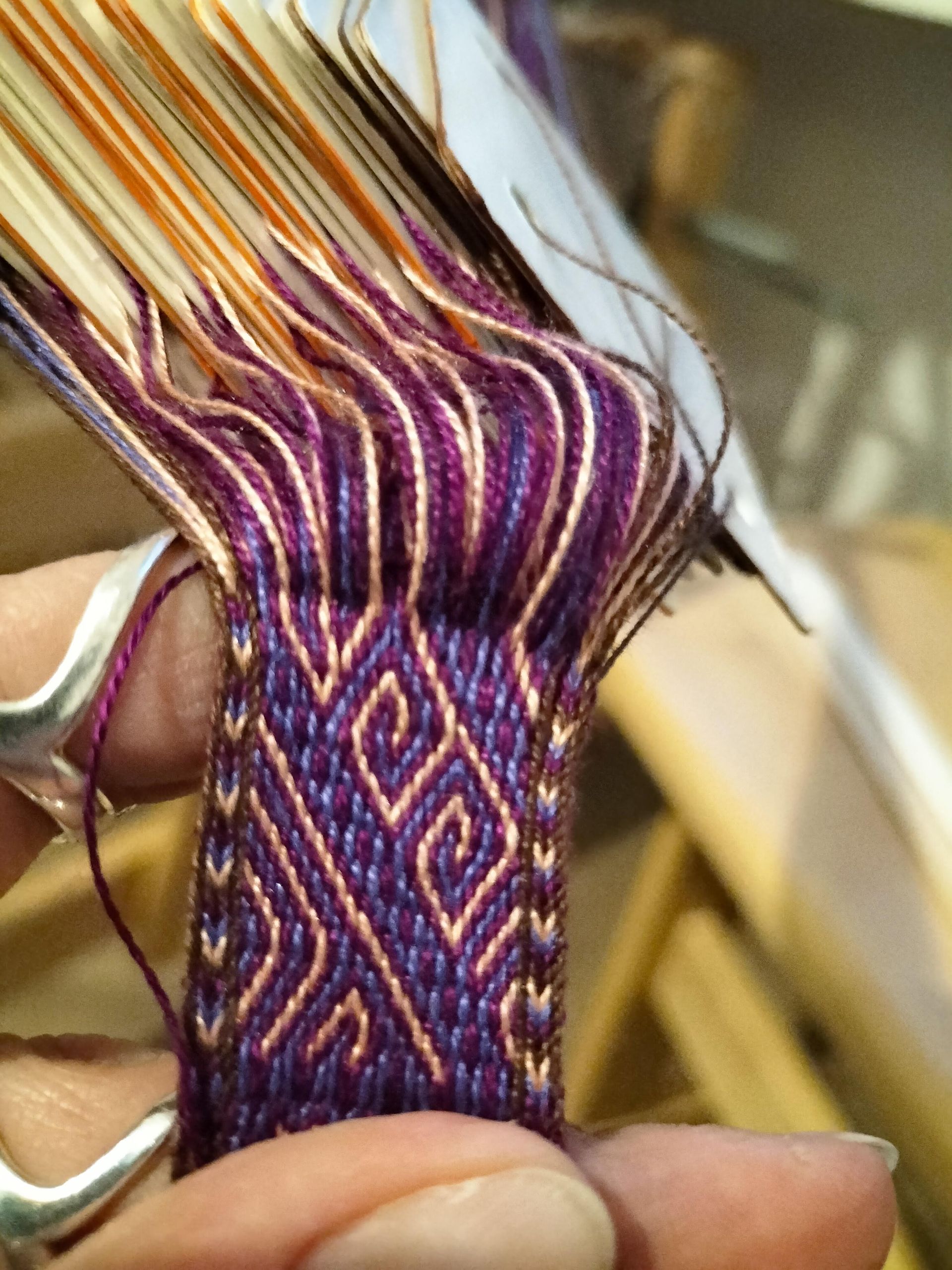 Close-up van een geweven textiel met een geometrisch paars en goud ontwerp.