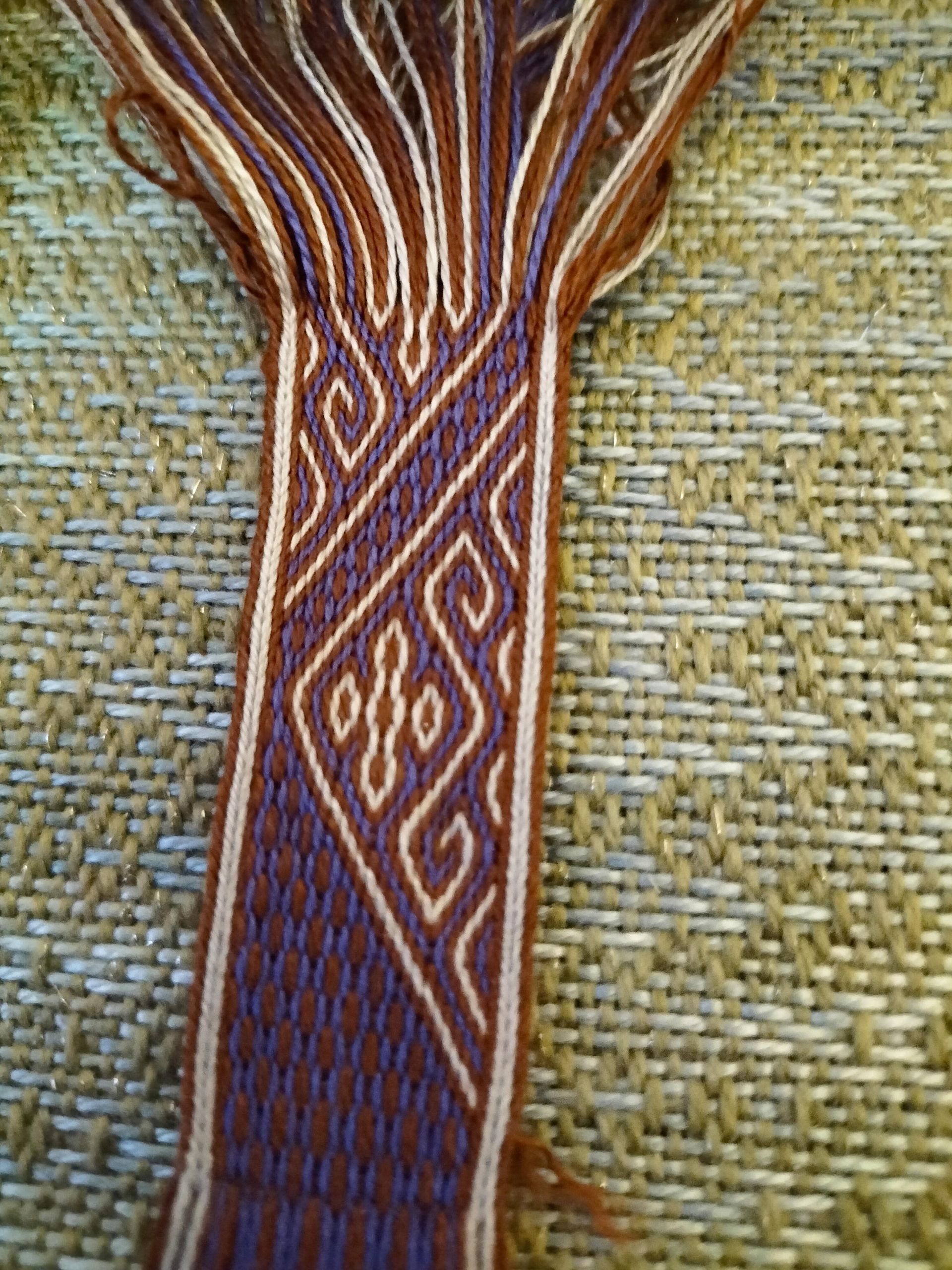 Geweven textiel in bruin, blauw en bruin met geometrische patronen.