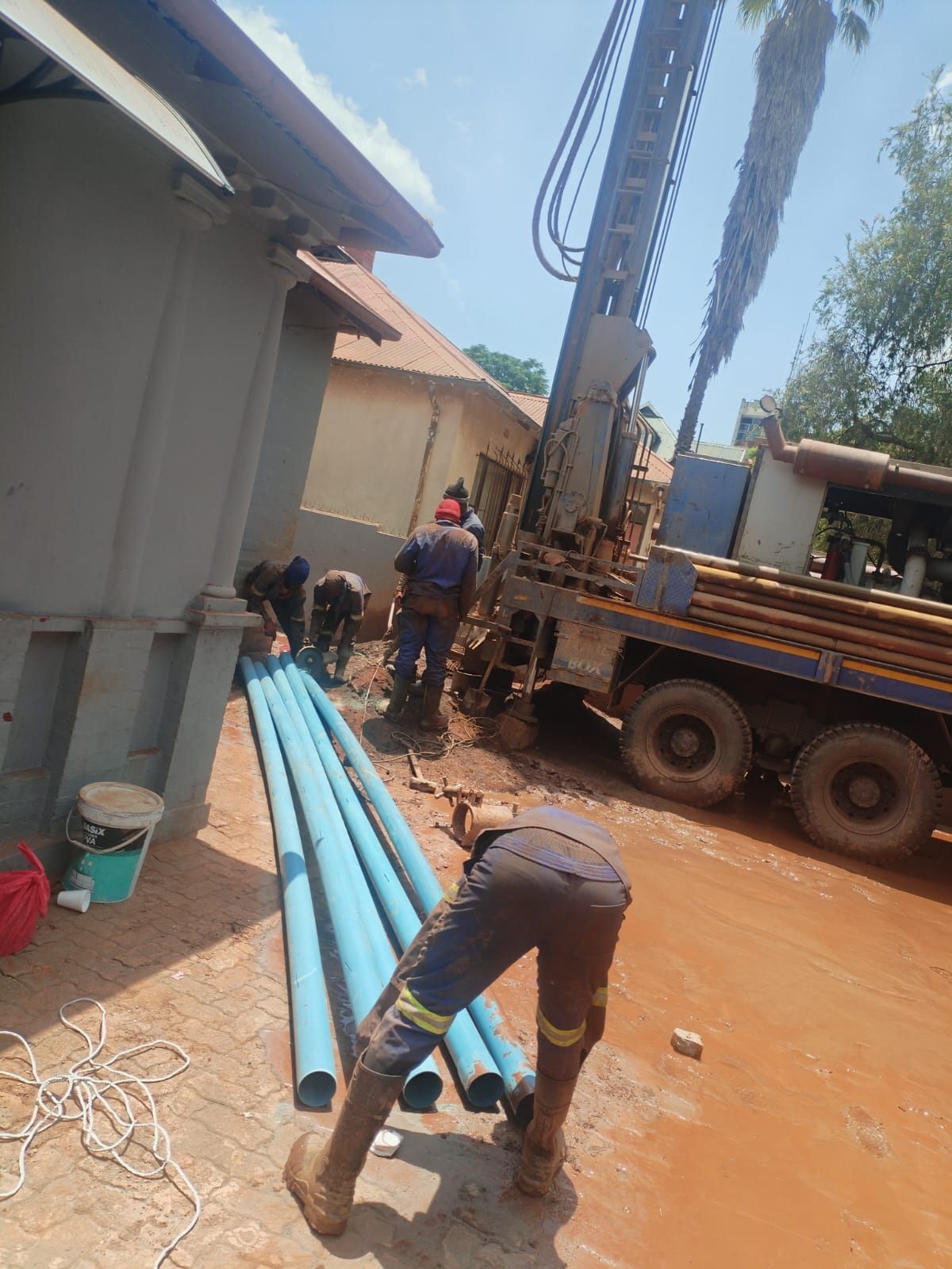 A group of people are working on a pole in the dirt.