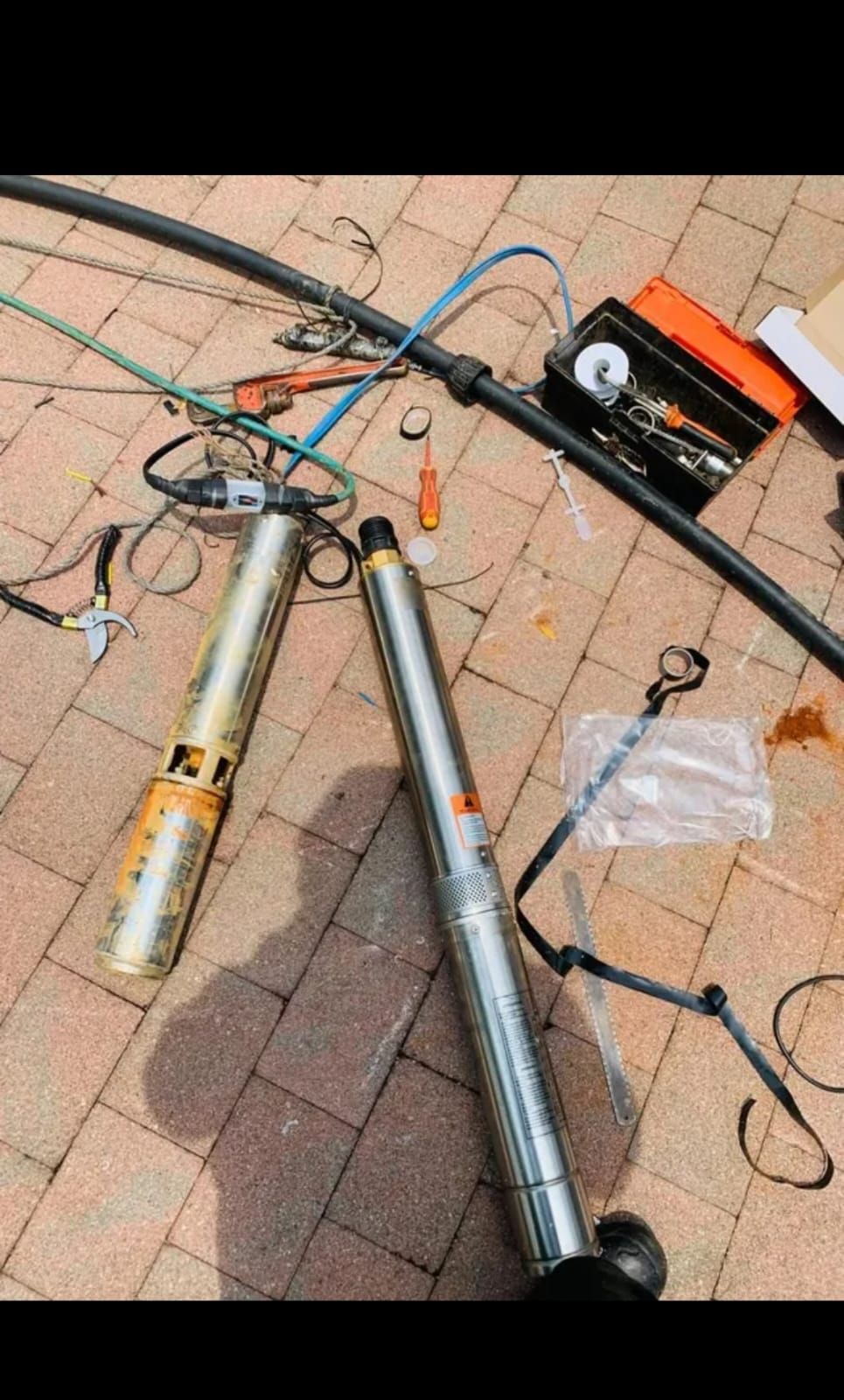 A water pump is being repaired on a brick sidewalk.