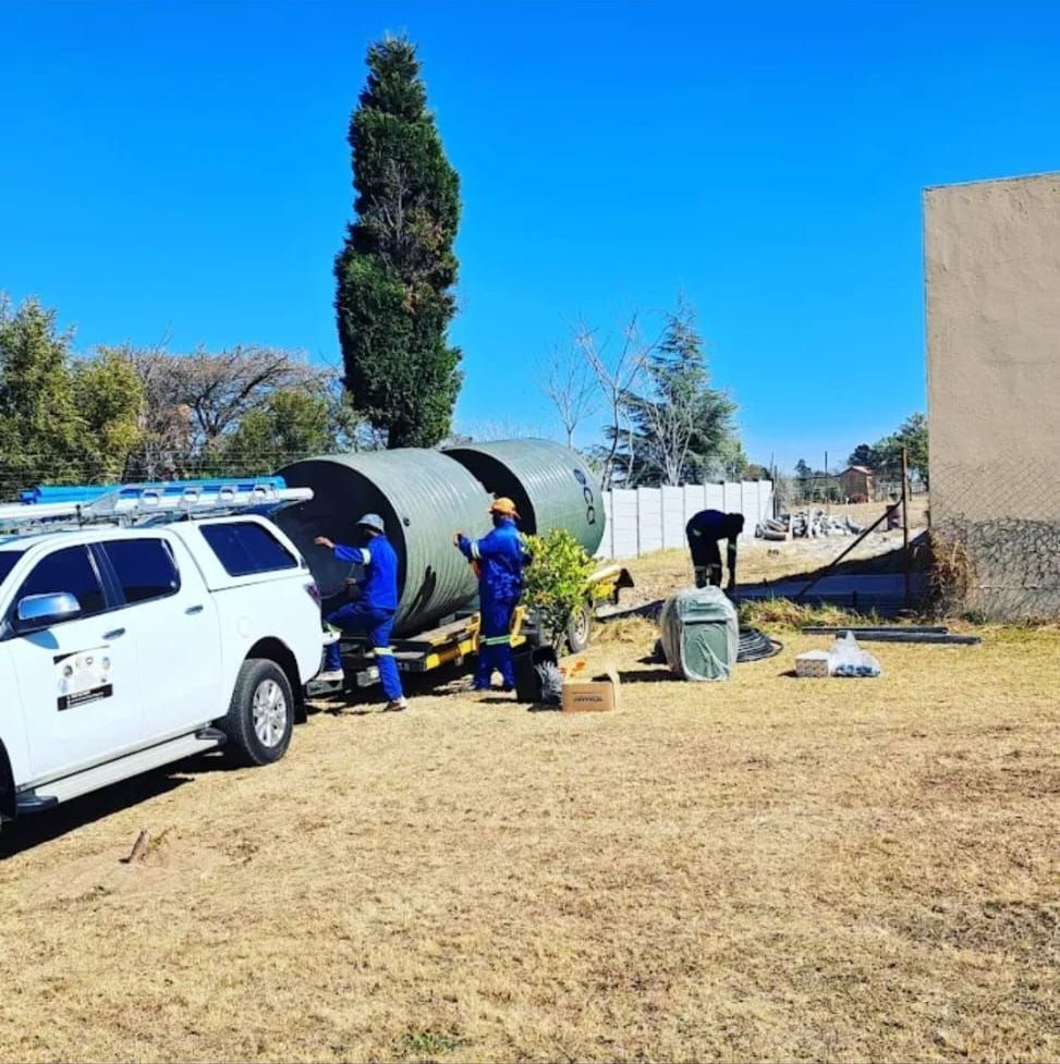 A group of people are working on a large pipe in a field.