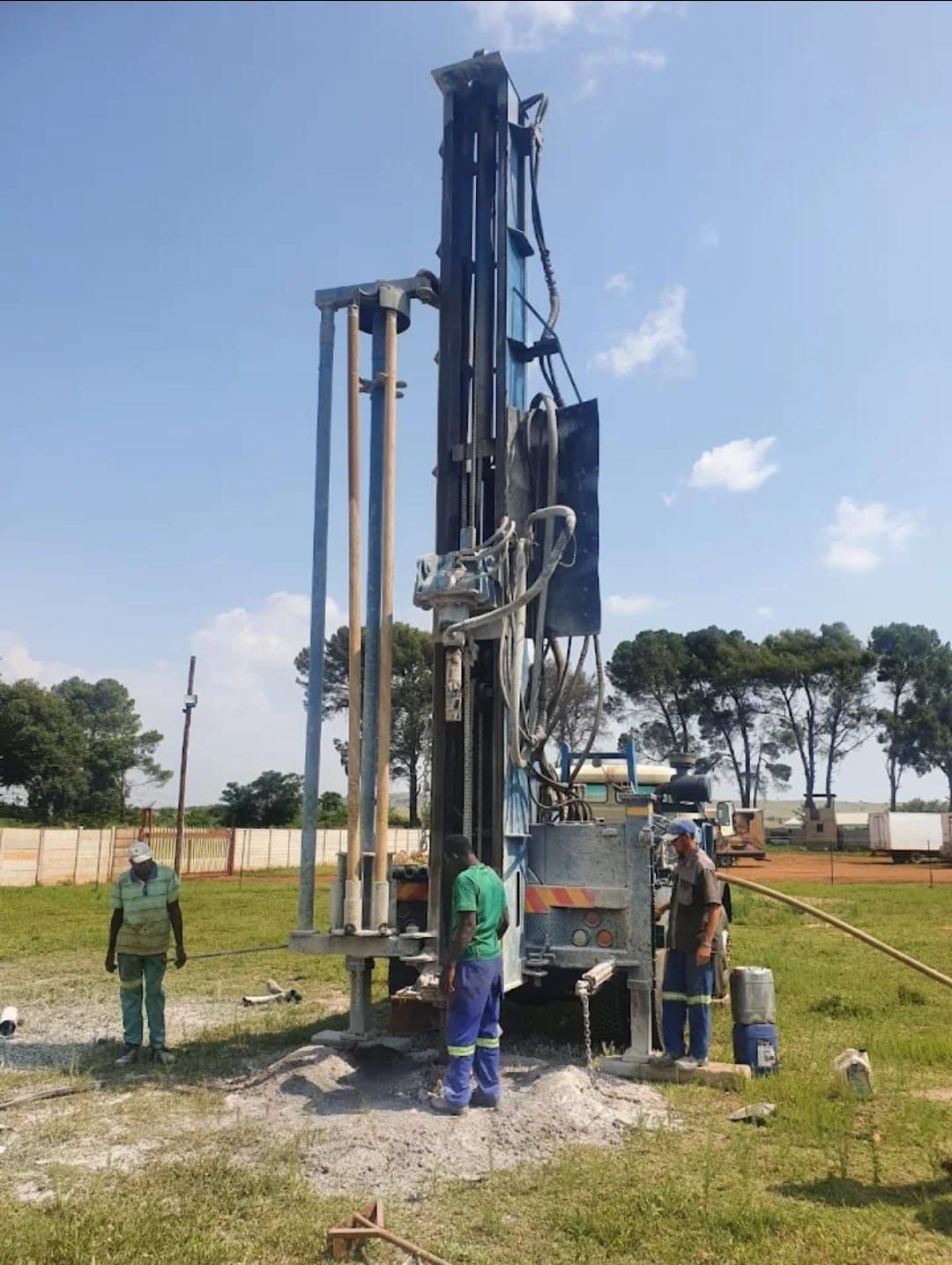 A group of people are working on a borehole in the dirt.