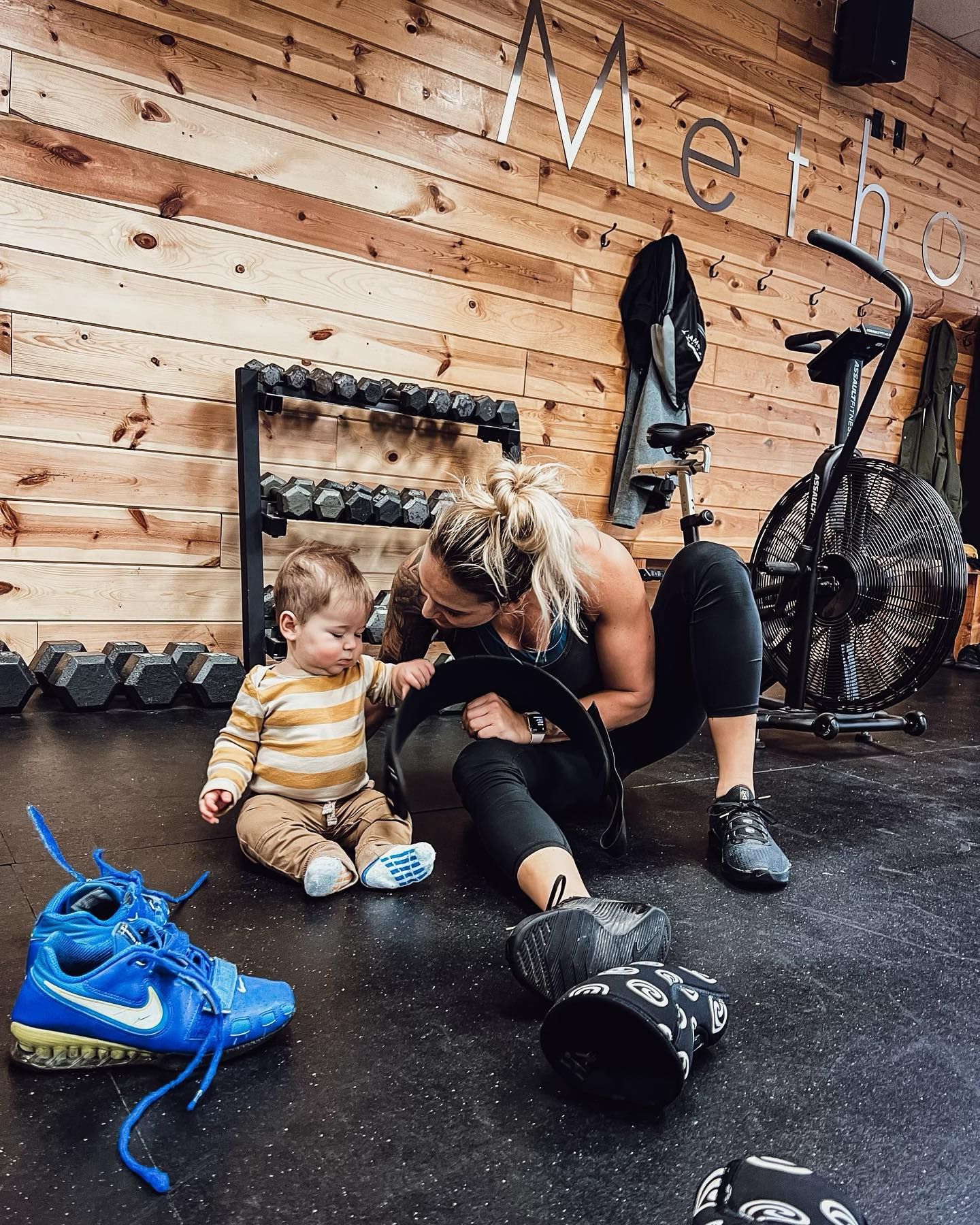 A woman and a baby are sitting on the floor in a gym.