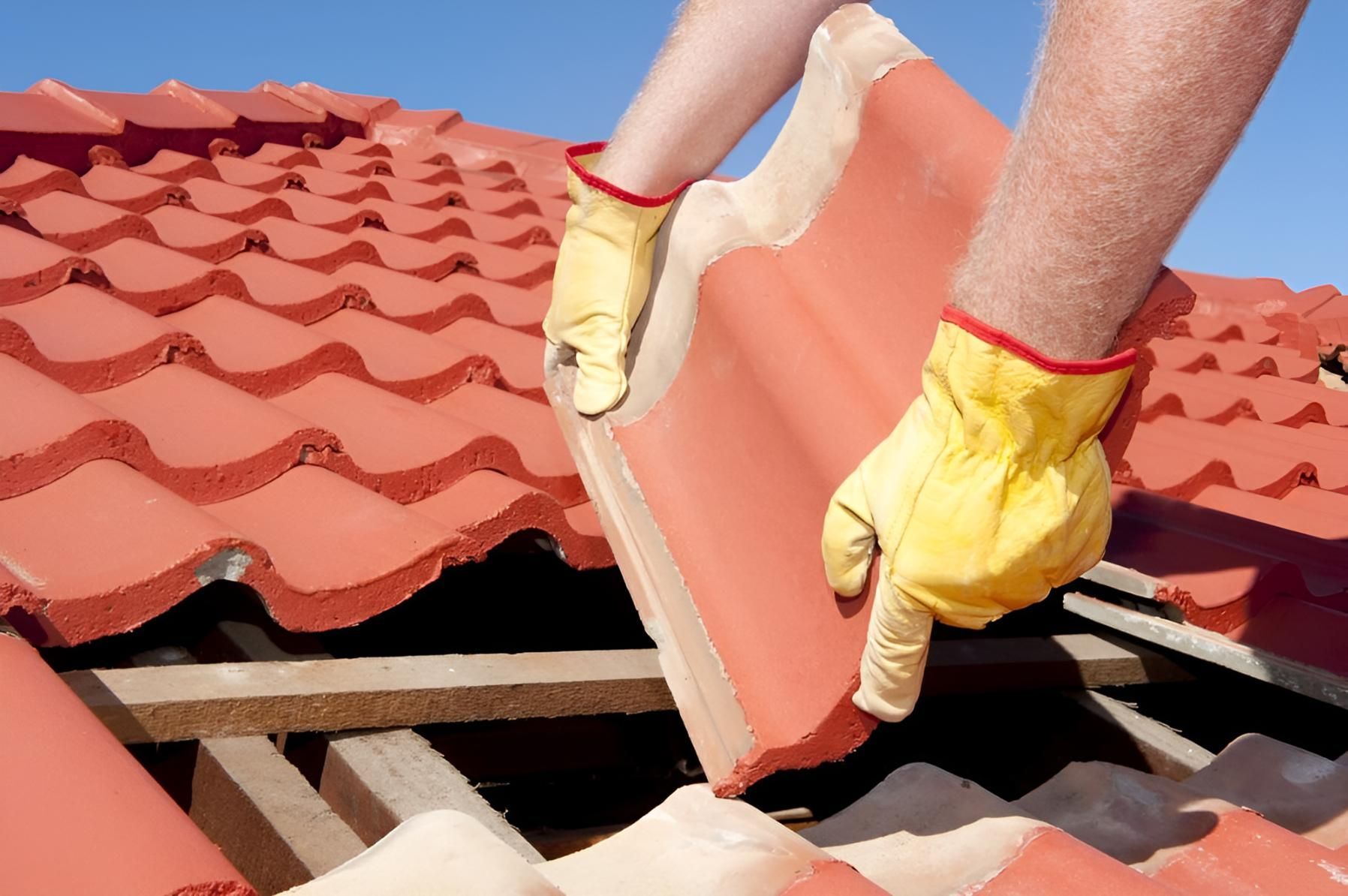 A Person Wearing Yellow Gloves Is Working On A Roof — The Good Guys Roof Restorations In Shellharbour, NSW