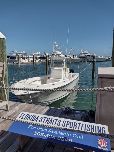 White sportfishing boat docked at a marina, blue sign for Florida Straits Sportfishing.