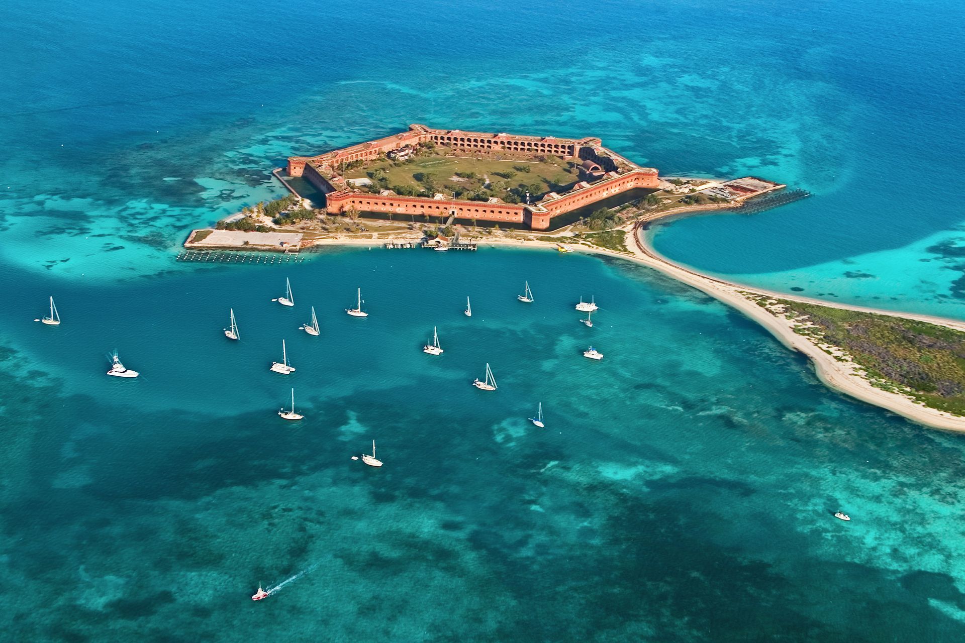 Aerial view of Fort Jefferson in the Dry Tortugas National Park, surrounded by turquoise water and sailboats.