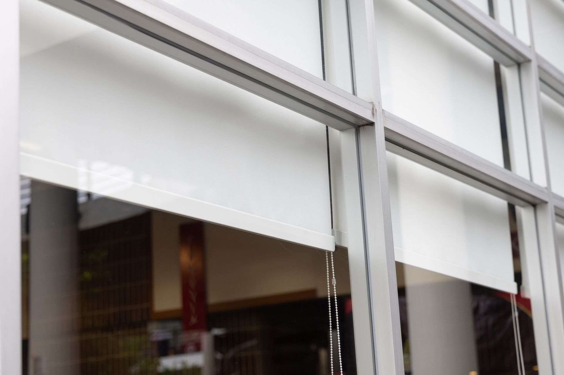 Tende a rullo bianche all'interno del telaio di una finestra.