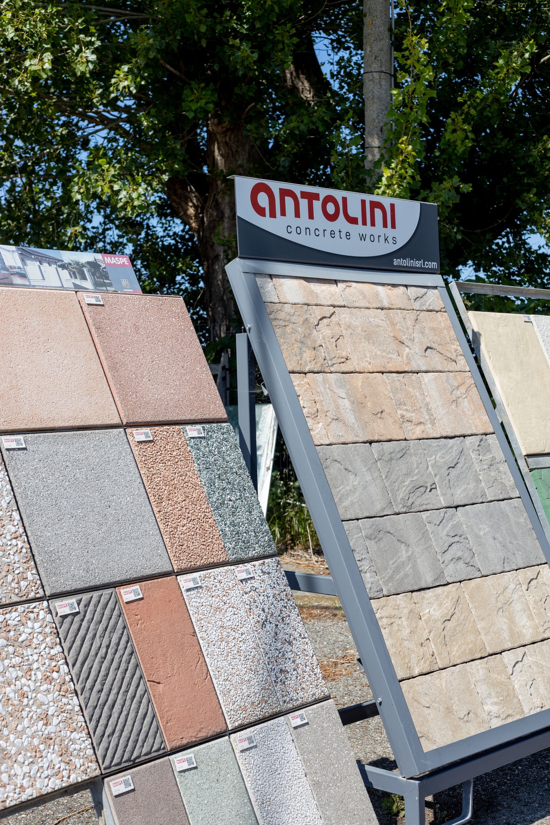 Esposizioni di piastrelle in pietra all'esterno, caratterizzate da vari colori e texture, con l'insegna