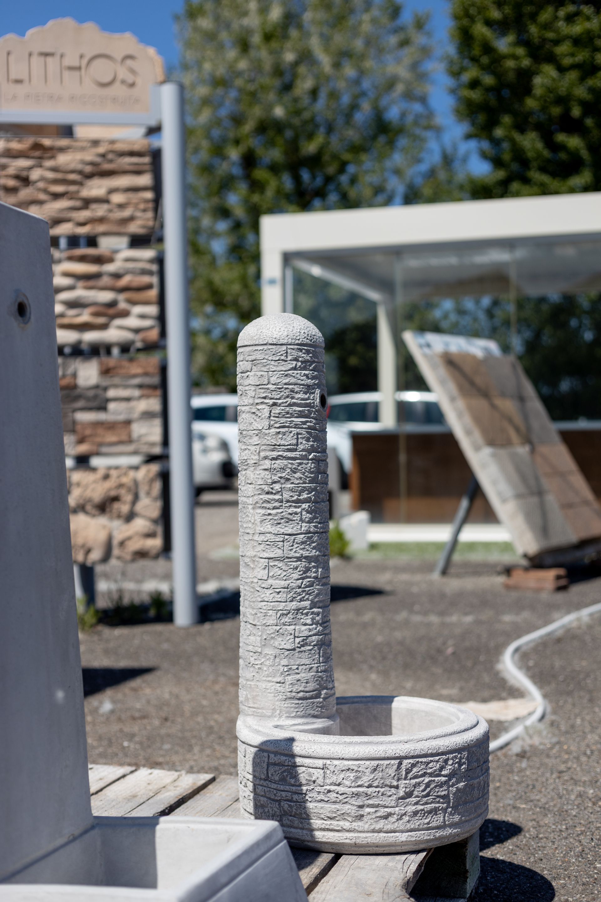 Fontana in pietra con pilastro scolpito, ciotola e insegna in posizione esterna.