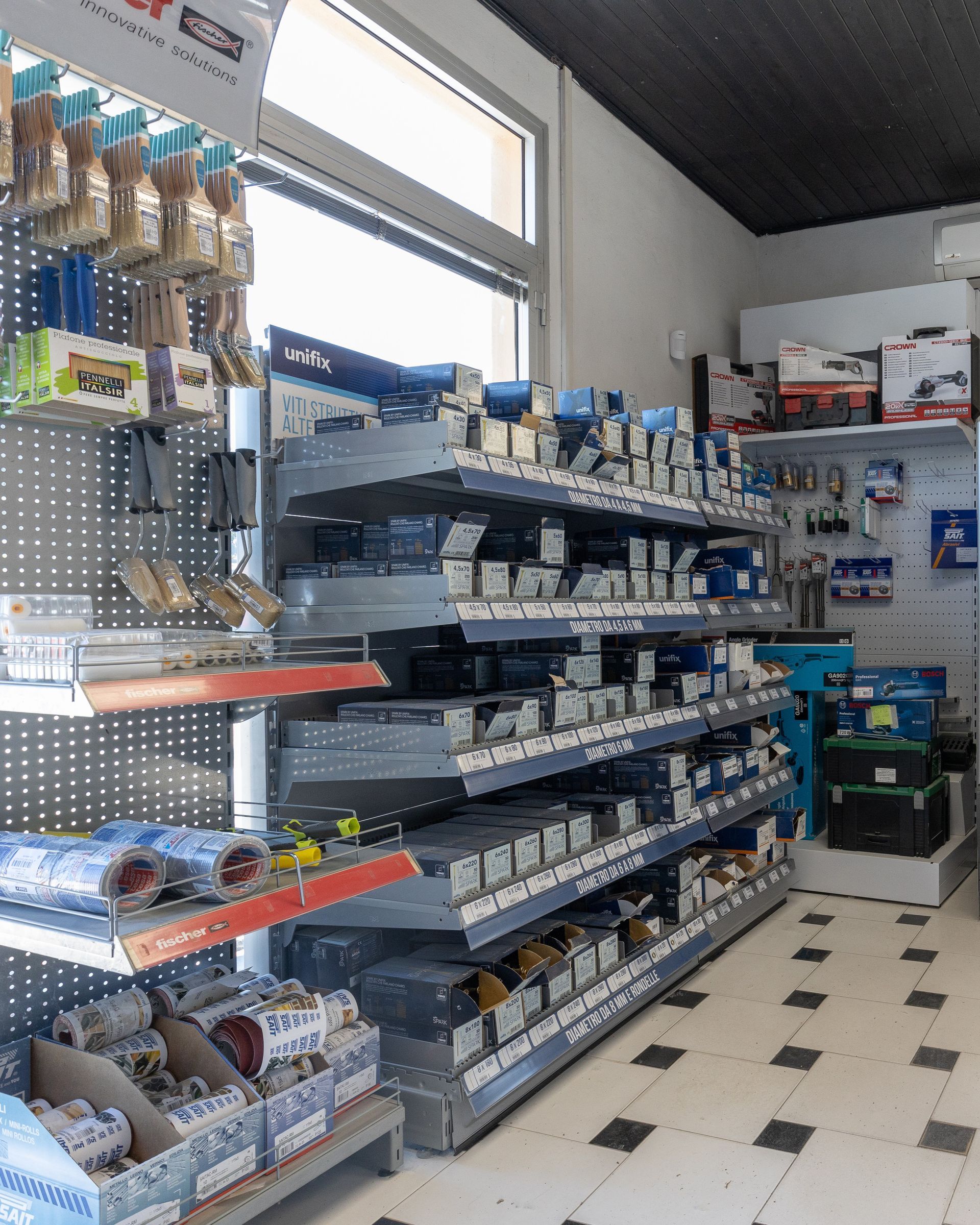 Interno di un negozio di ferramenta con scaffali pieni di vari utensili e forniture.