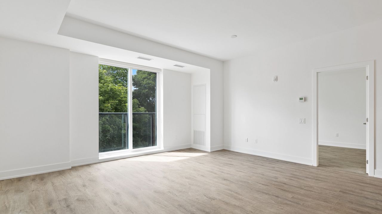 Bright and spacious empty apartment with large window and wooden floors, ready for first-time renter