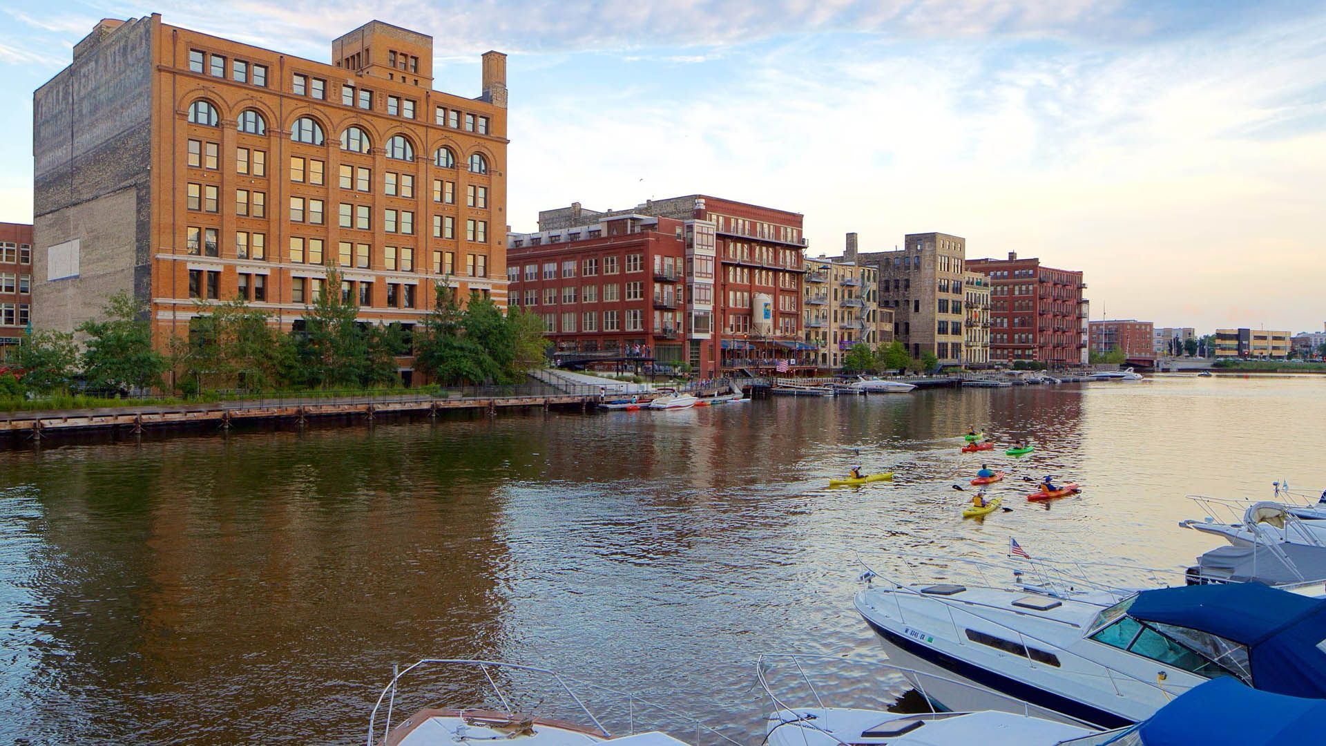 Experience Milwaukee from the water with a fun kayaking tour along the river. Group kayaking on the Milwaukee River with the downtown skyline in the background.