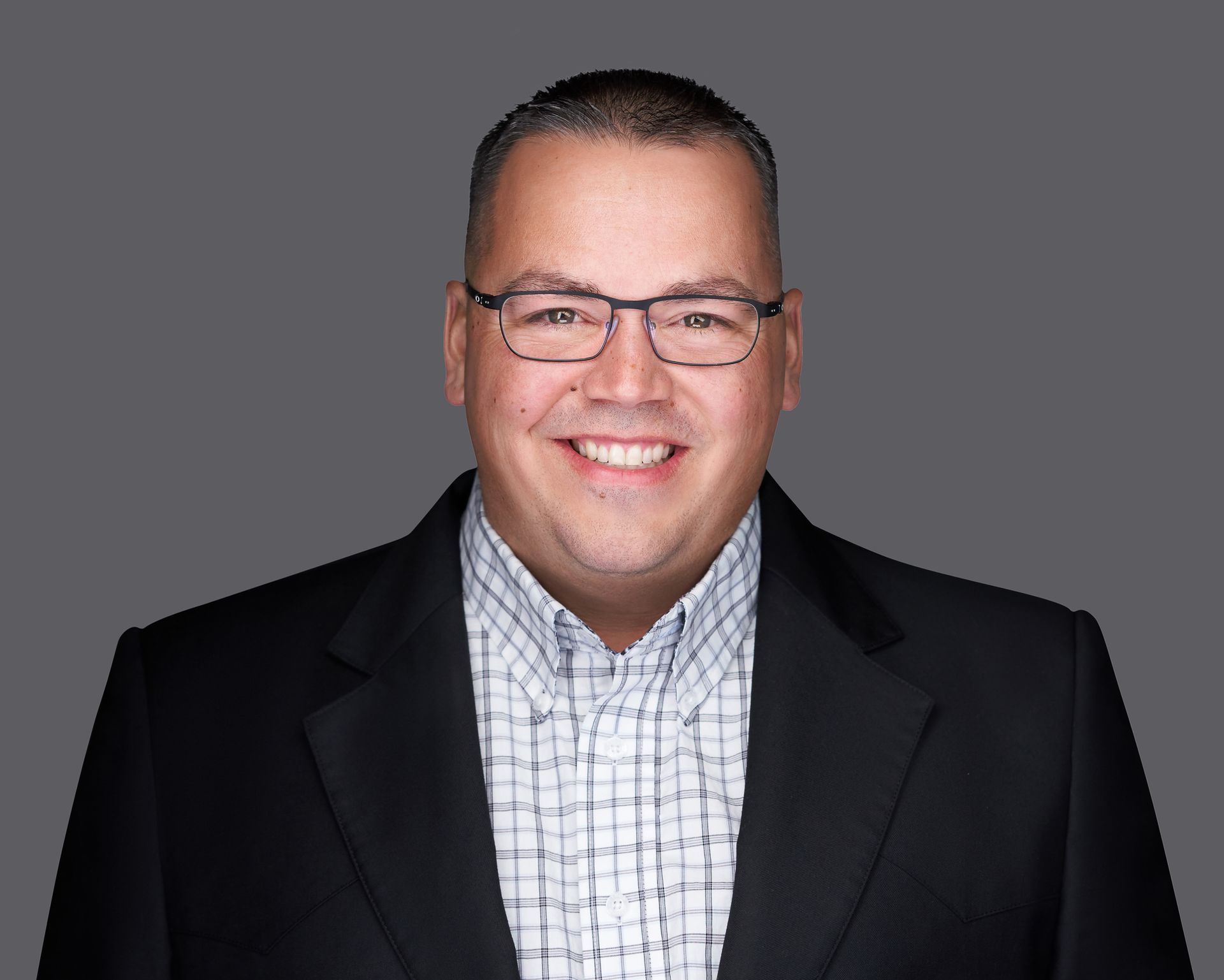 A man wearing glasses and a suit is smiling for the camera.
