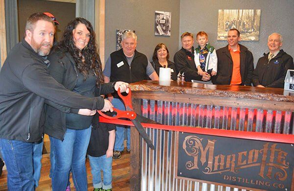 A group of people are cutting a red ribbon in front of a sign that says marco