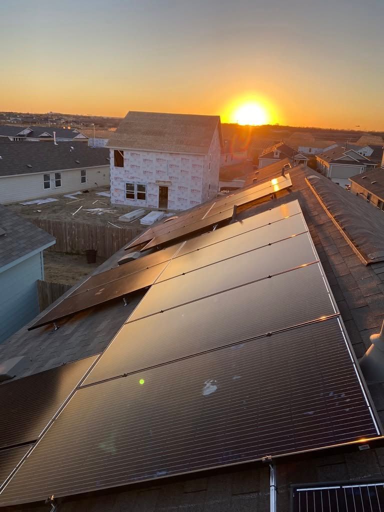Sunset over rooftops with a large solar panel array in the foreground
