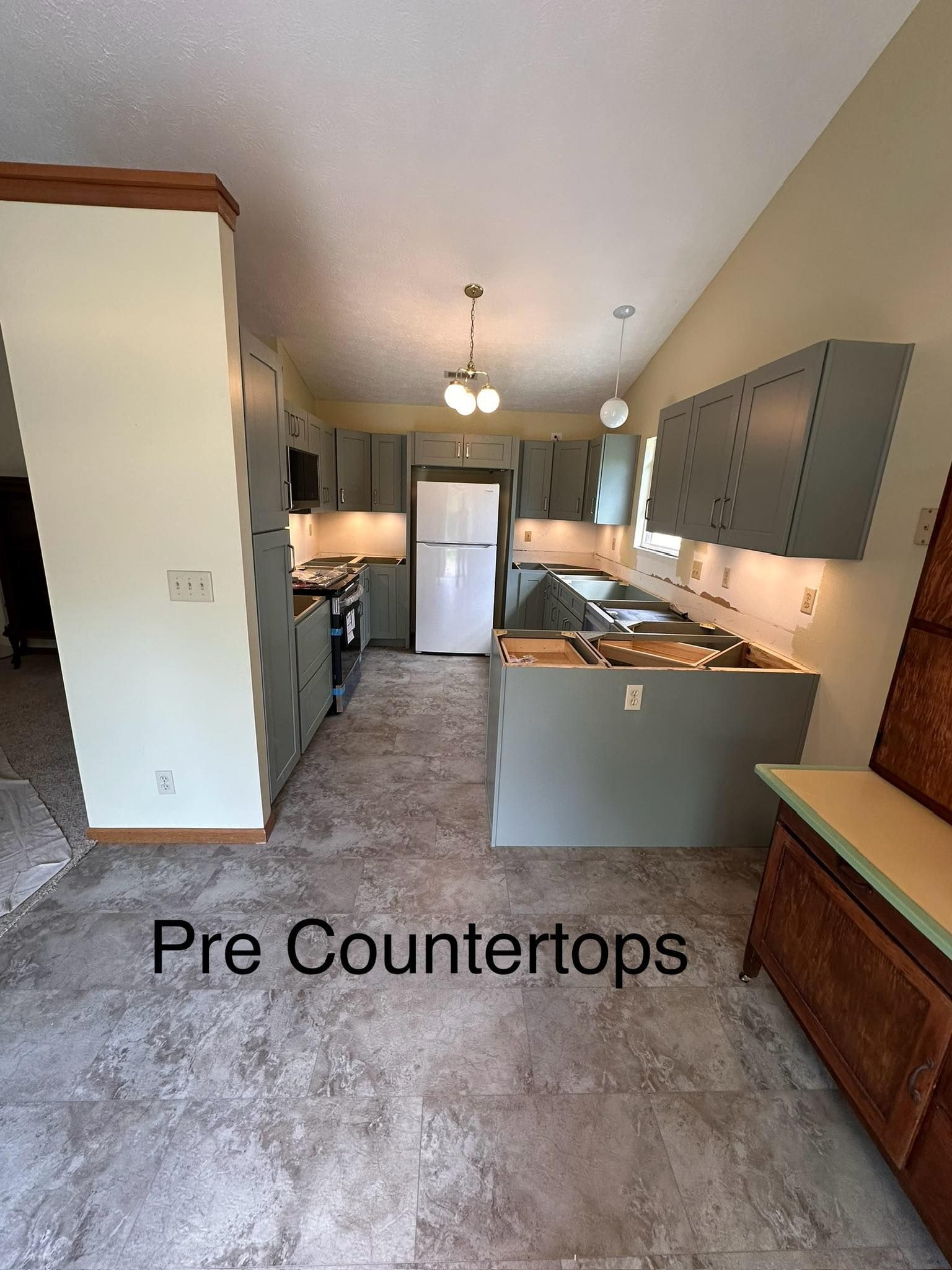 A kitchen with a refrigerator , stove , sink , and cabinets.