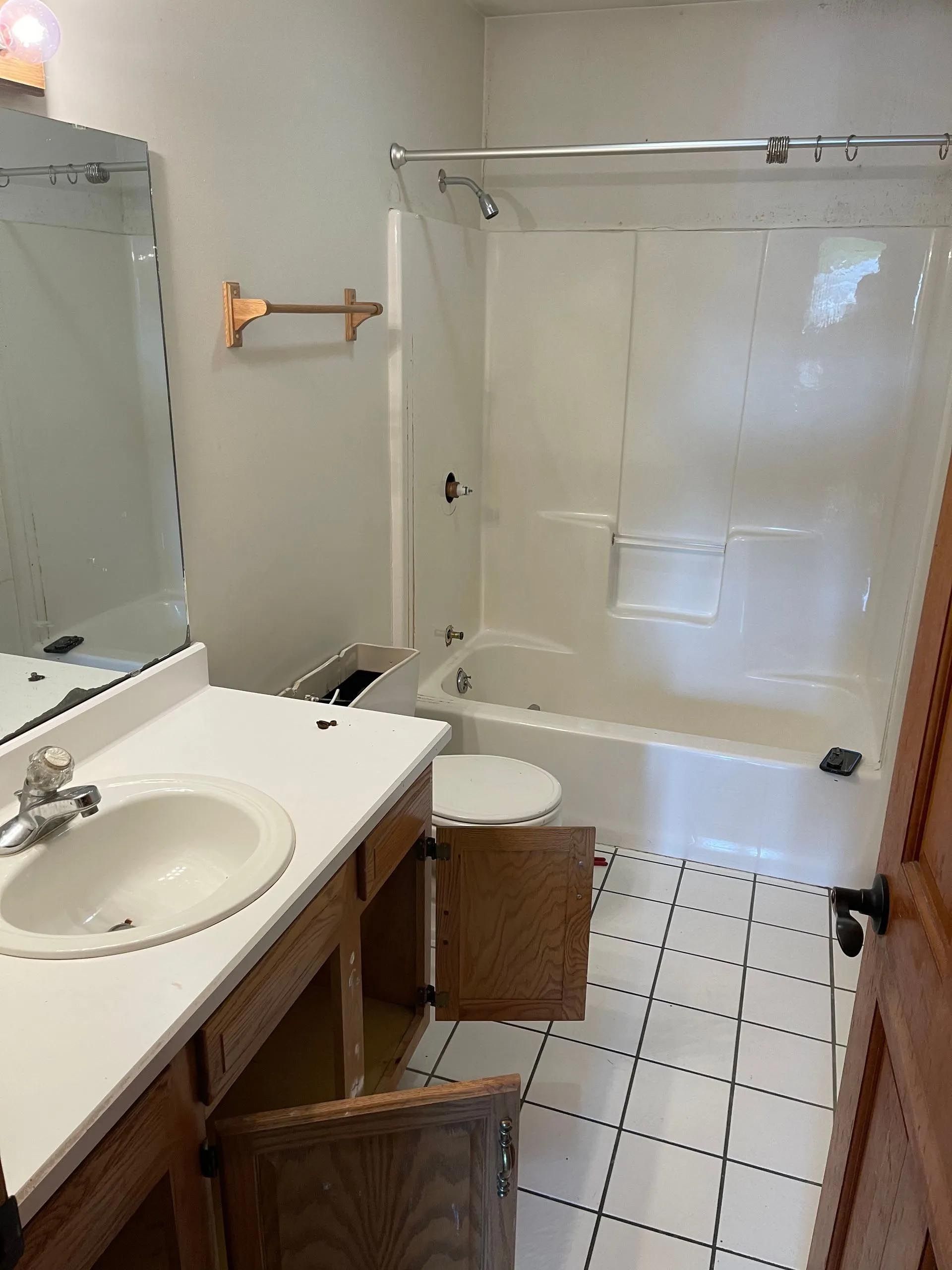 A bathroom with a sink , toilet , tub and mirror