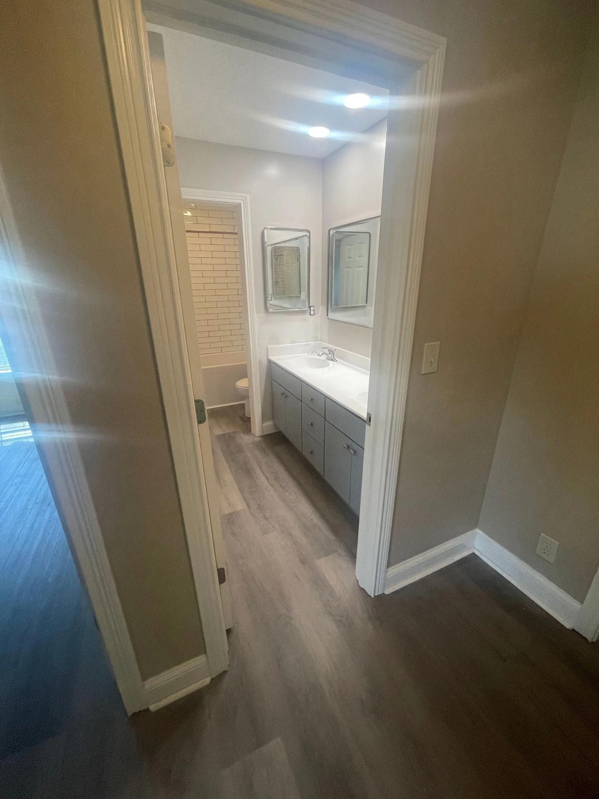 A bathroom with a sink , mirrors , and a walk in shower.