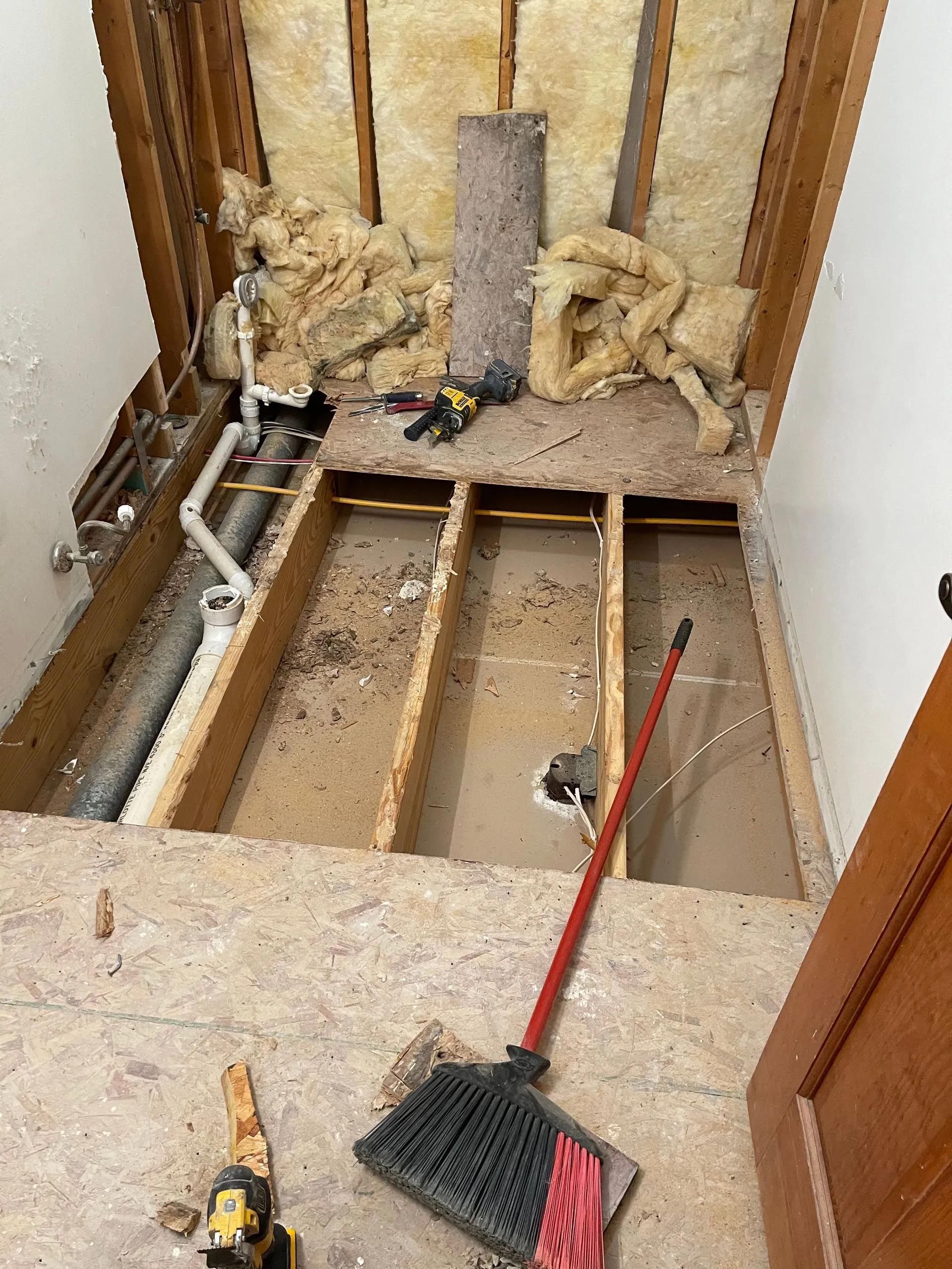 A bathroom under construction with a broom and tools on the floor.