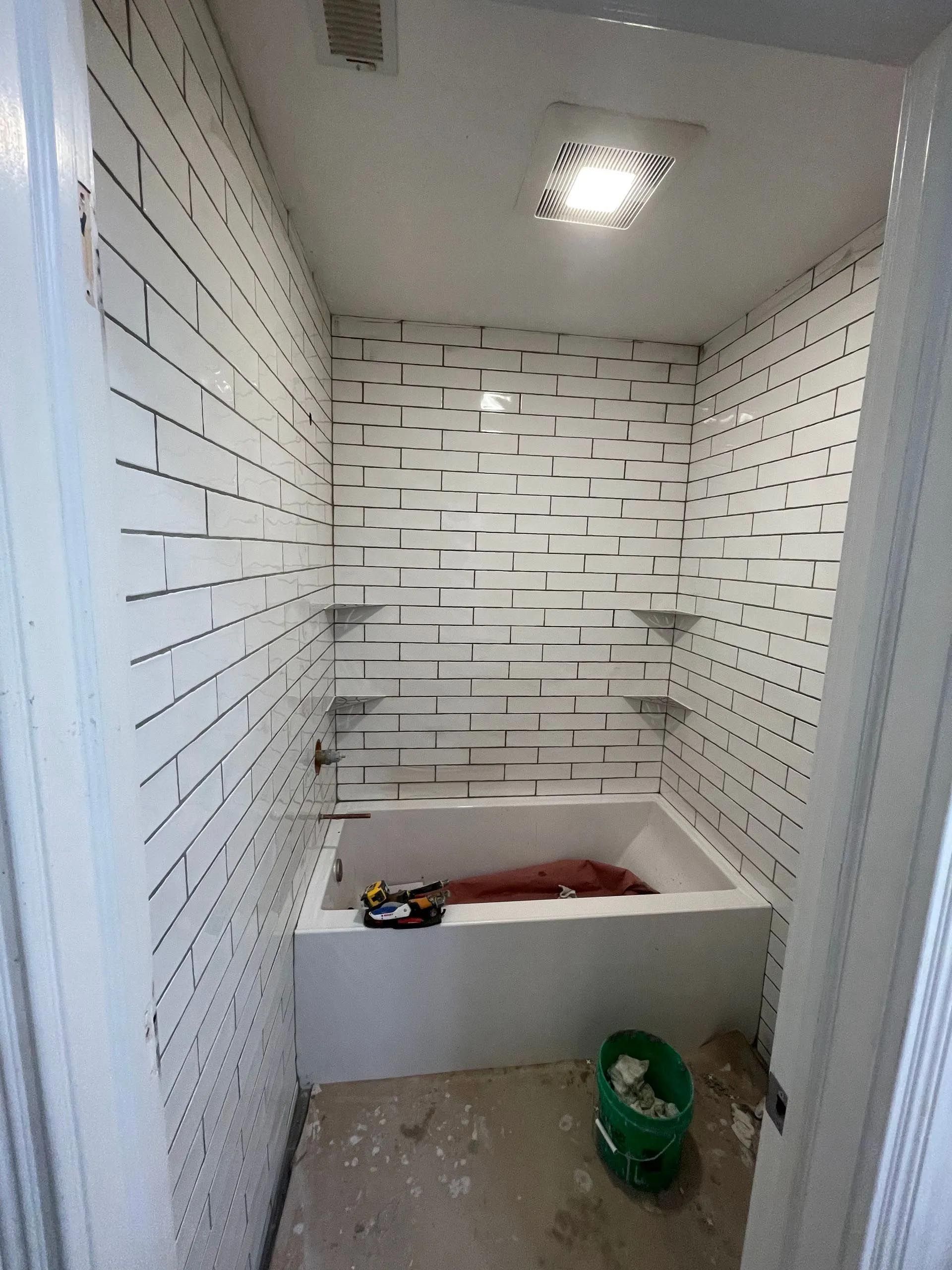 A bathroom with white brick walls and a bathtub.