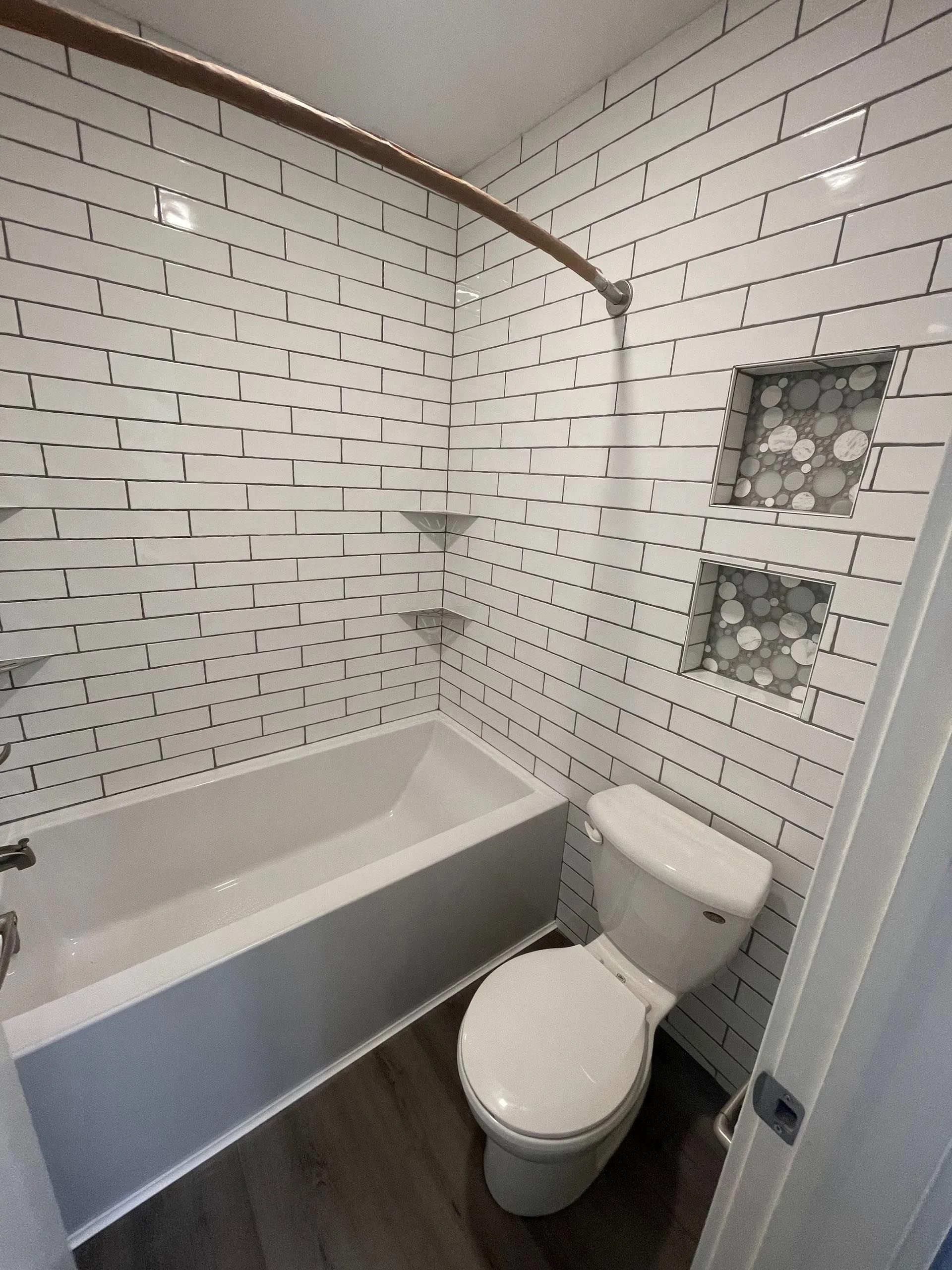 A bathroom with a toilet , bathtub and shower.