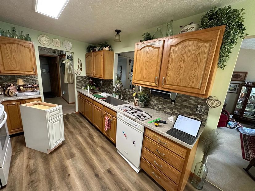 A kitchen with wooden cabinets and a laptop on the counter.