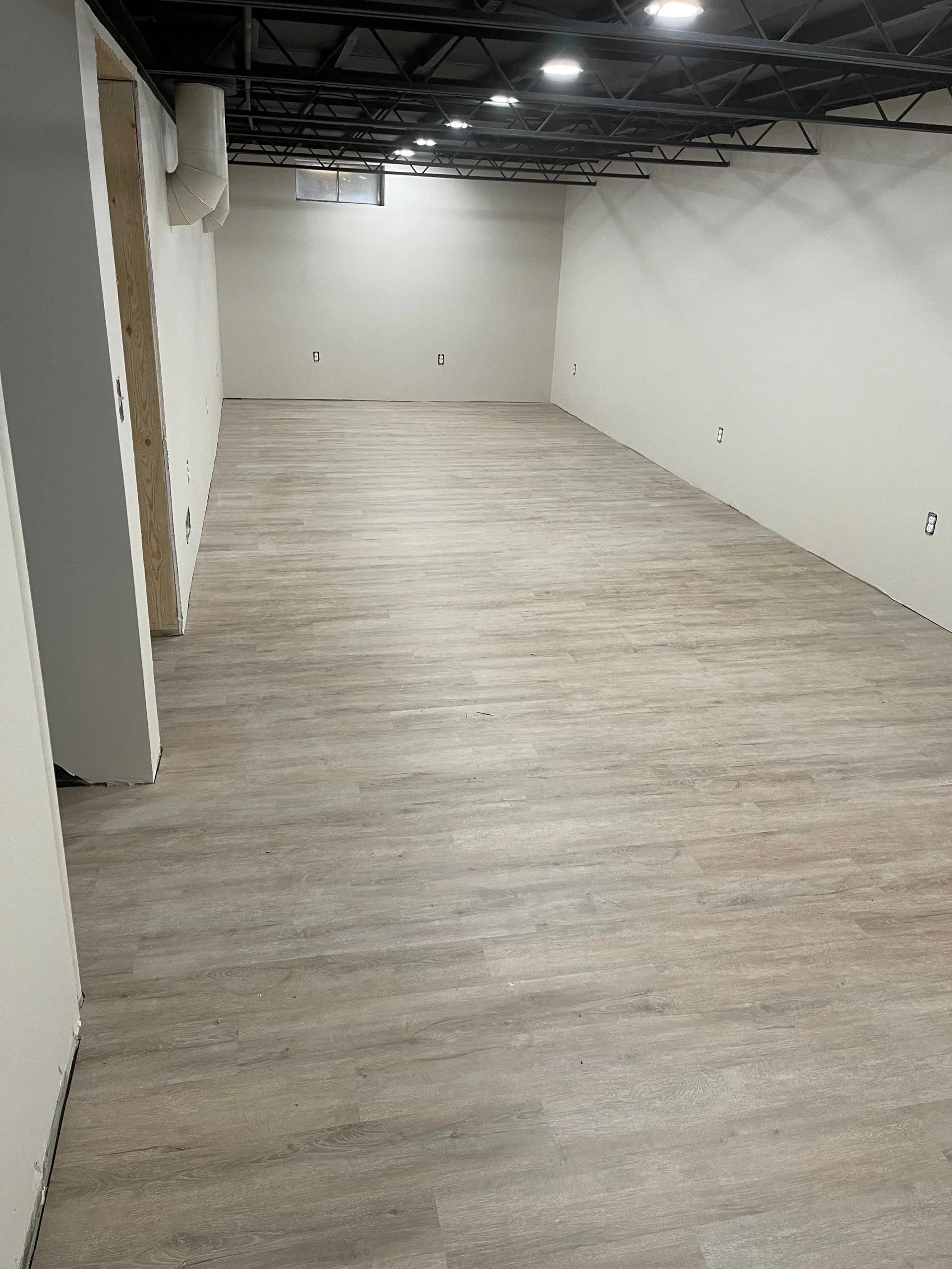 A large empty room with a wooden floor and white walls.